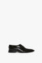 Victoria Beckham's Pointy Toe Flat Lace Up In Black Brushed Leather against a white background. This design features an Oxford brogue pattern and a pointy toe silhouette for added sophistication.