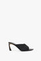 A black woven high-heel mule with an open toe and a V-cut design in textured raffia, the V Cut Mule In Black Raffia by Victoria Beckham, is displayed against a white background.