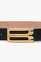 A contemporary belt crafted from smooth calf leather, featuring an ornate gold buckle with two parallel rectangular designs. The Jumbo Frame Belt In Black Leather by Victoria Beckham exemplifies this style.