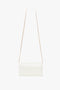 Victoria Beckham Exclusive Wallet On Chain In Ivory Croc-Effect Leather with a thin gold chain strap against a white background.