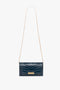 A small dark blue Wallet On Chain In Midnight Croc-Effect Leather by Victoria Beckham, featuring a gold metal clasp and a thin, gold removable chain strap.