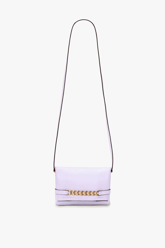 A light lilac shoulder bag with a long, detachable strap and gold accents on the front, perfect for those who love a stylish EXCLUSIVE Mini Chain Pouch With Long Strap In Lilac Leather by Victoria Beckham.