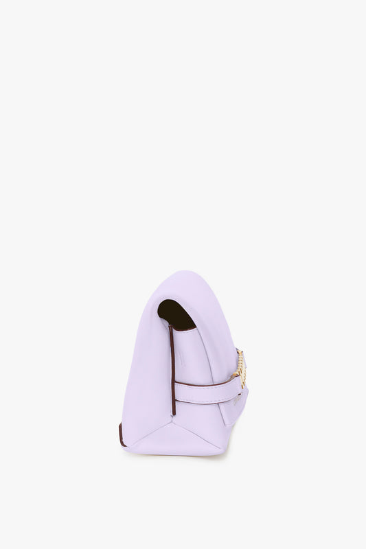 Side view of a lilac handbag, known as the EXCLUSIVE Mini Chain Pouch With Long Strap In Lilac Leather by Victoria Beckham, featuring a rounded top, gold chain detail, dark interior lining, and a detachable strap.