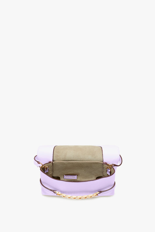 Purple and beige EXCLUSIVE Mini Chain Pouch With Long Strap In Lilac Leather by Victoria Beckham with an open top, revealing its interior compartments. A gold chain is attached to the front of the lilac bag, complemented by a detachable strap for versatile styling.