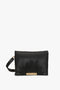 A Puffy Jumbo Chain Pouch In Black Leather by Victoria Beckham with an adjustable shoulder strap and gold detailing on the front.