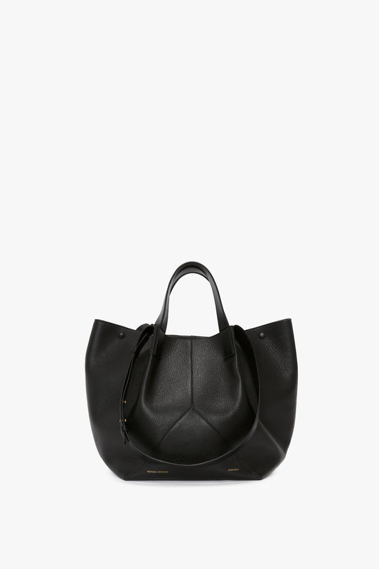 A luxurious black W11 Medium Tote In Black Leather crafted from grained leather with two handles and a textured finish, displayed against a plain white background. Versatile styling makes it perfect for any occasion. This exquisite piece is designed by Victoria Beckham.