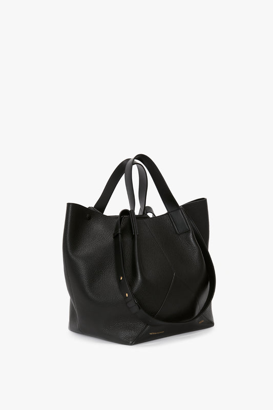 A black leather W11 Medium Tote In Black Leather by Victoria Beckham with versatile styling, featuring two handles and an attached smaller pouch, displayed against a white background.