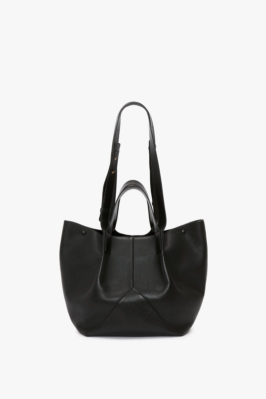 A black, luxurious grained leather W11 Medium Tote In Black Leather by Victoria Beckham with two shoulder straps is displayed against a white background, showcasing its versatile styling.