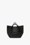 A large black luxury grained leather W11 Jumbo Tote Bag In Black Leather by Victoria Beckham with dual handles, an open top design, and an internal pocket compartment.