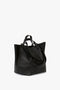 W11 Jumbo Tote Bag In Black Leather by Victoria Beckham made from luxury grained leather, with dual top handles and an adjustable shoulder strap, placed against a plain white background.