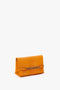 Bright mandarin Mini Chain Pouch Bag With Long Strap In Mandarin Leather by Victoria Beckham UK, featuring a mini chain pouch detail on the front and small brand text at the bottom.