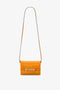 Bright mandarin orange Mini Chain Pouch Bag With Long Strap In Mandarin Leather by Victoria Beckham UK, featuring a long strap and buckle detail on the front for added style.