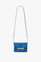 Mini Chain Pouch Bag With Long Strap In Sapphire Blue by Victoria Beckham UK with a long strap and gold chain detail on the front. This stylish piece also features a detachable strap, offering versatility for any occasion.