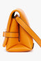 Side view of a bright mandarin leather Mini Chain Pouch Bag With Long Strap In Mandarin Leather by Victoria Beckham UK, featuring a top zipper closure and a chic mini chain pouch.