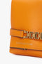 Close-up of an orange **Mini Chain Pouch Bag With Long Strap In Mandarin Leather** featuring gold-tone hardware and a long strap with chain detail. The bag's bright mandarin hue is complemented by the brand name embossed in silver on the leather: **Victoria Beckham UK**.