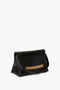 A black Chain Pouch Bag With Strap In Black Croc-Effect Leather by Victoria Beckham with an embossed calf-leather crocodile texture and a gold chain accent on the front, featuring a shoulder strap, set against a plain white background.