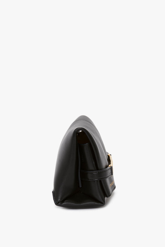 Side view of a Mini Chain Pouch With Long Strap In Black Leather by Victoria Beckham with a gold-tone buckle on a white background.