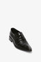 A single black, crocodile-patterned dress shoe with a pointed toe and black laces on a white background showcases the elegance of the Pointy Toe Flat Lace Up In Black Croc-Effect Leather by Victoria Beckham.