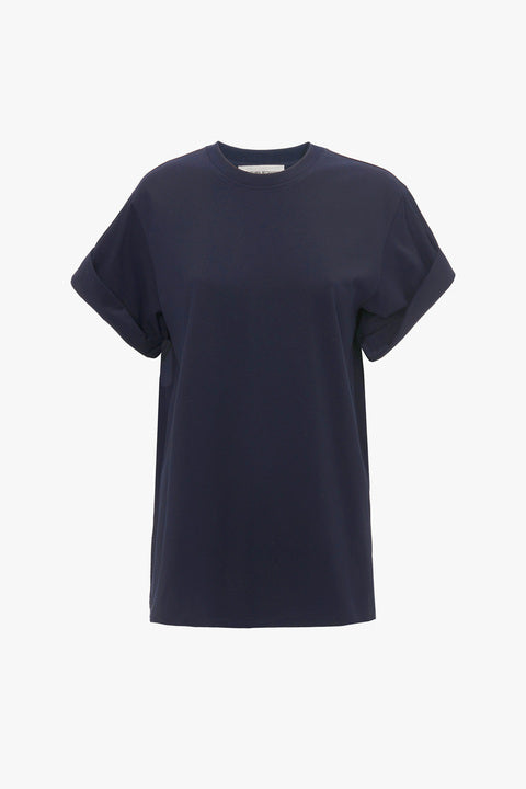 An Asymmetric Relaxed Fit T-Shirt In Navy by Victoria Beckham with rolled-up sleeves and the Victoria Beckham monogram is displayed against a plain white background.