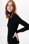 A person with long red hair is wearing a Poloneck Bodysuit In Black by Victoria Beckham made from Merino Wool. The background is plain white.