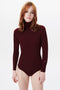 A person with shoulder-length hair wears a Victoria Beckham Poloneck Bodysuit In Bordeaux made from soft Merino wool against a plain white background.