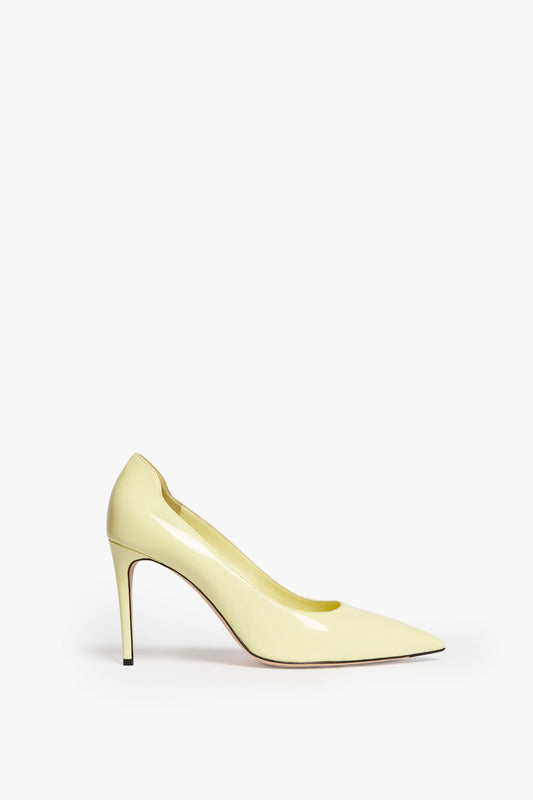 A yellow VB 90mm Pump In Pale Lemon with a pointed toe and glossy finish, featuring a sleek 90mm stiletto heel, viewed from the side by Victoria Beckham.