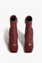 A pair of Victoria Beckham Iona Boots In Dark Red lambskin leather with side zippers and peep toe design, viewed from above against a white background.