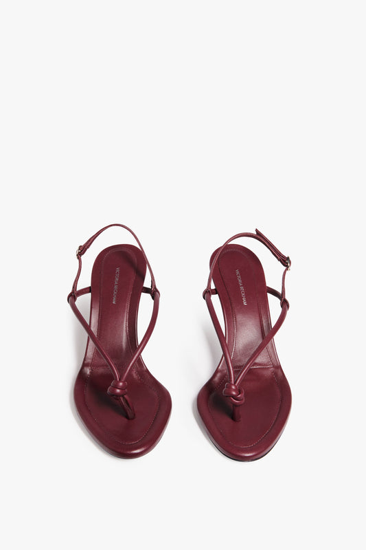 Pair of burgundy heeled sandals crafted from luxurious Bordeaux nappa leather with thin straps and square toes, displayed from above on a white background. The product is "Estelle in Bordeaux" by Victoria Beckham.