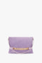 A Victoria Beckham Chain Pouch Bag with Strap in Lilac Suede featuring a gold chain detail at the front and a single shoulder strap, crafted from fine Italian leather.