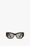 A pair of Victoria Beckham Sculptural Frame Sunglasses In Black made from glossy black acetate with dark tinted lenses is centered on a white background, exuding the sleek elegance synonymous with Victoria Beckham.