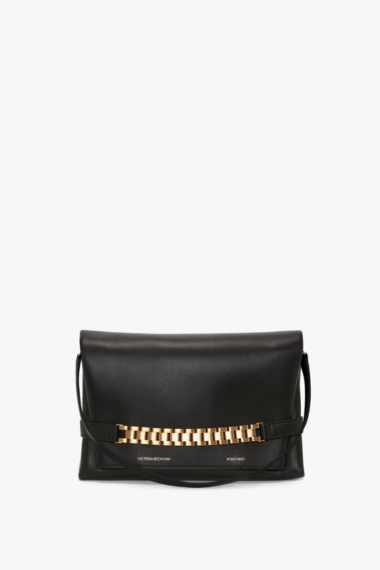 A Victoria Beckham Chain Pouch with Strap In Black Leather with a gold chain detail across the front, offering minimalist design and versatile styling.