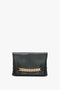 Chain Pouch Bag In Black Leather with a gold chain detail across the front and elegant gold-tone hardware. The names "Victoria Beckham" and "Krypton" are printed in small gold letters at the bottom.