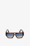 Rectangular brown Victoria Beckham V Plaque Frame Sunglasses In Dark Brown Horn with sculpted blue gradient lenses displayed on a white background.