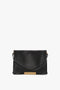 A Jumbo Chain Pouch Bag In Black Leather by Victoria Beckham, featuring a gold chain accent on the front and a single detachable shoulder strap.