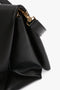 Close-up of a Jumbo Chain Pouch Bag In Black Leather by Victoria Beckham with a gold clasp and adjustable, detachable strap.