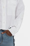 Close-up of a person wearing a white Victoria Beckham Cropped Patch Pocket Shirt In White and blue jeans. The person's hand is in their jeans pocket.