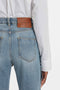 Close-up of a person wearing light blue jeans with a brown label reading "Victoria Beckham" and a Cropped Patch Pocket Shirt In White tucked in. The image is focused on the back pocket area.