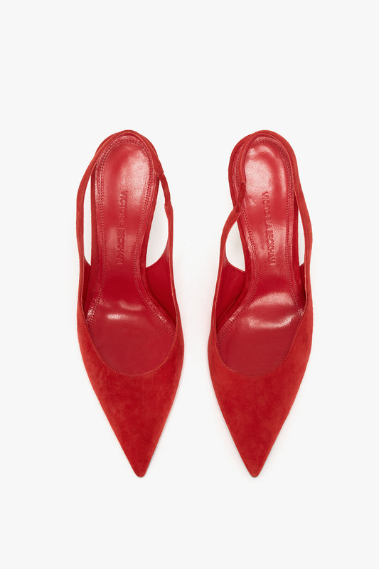 A pair of Victoria Beckham V Cut Slingback Pump In Orange Suede with pointed toes viewed from above against a white background, reminiscent of Victoria Beckham tailoring.