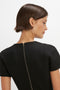 A person with short brown hair is seen from the back, wearing a black Spiral Fitted T-Shirt Dress In Black by Victoria Beckham, featuring a visible back zipper.