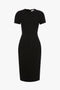 A black, matte bonded crepe Spiral Fitted T-Shirt Dress In Black with short sleeves and a simple, elegant design reminiscent of Victoria Beckham’s sophisticated style.