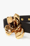 Close-up of a black fabric Exclusive Flower Belt In Black And Gold by Victoria Beckham featuring a large, shiny gold-plated, sculptural floral design buckle.