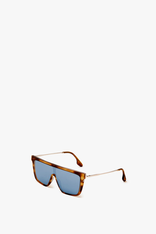 Rectangular Shield Sunglasses In Tortoise by Victoria Beckham with blue lenses and thin metal arms, featuring bold lines and a touch of tortoise-effect, positioned against a plain white background.