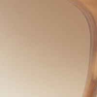 Close-up of a curved edge of a transparent, amber-colored object with a smooth surface, reminiscent of Classic Flat Top V Sunglasses in Honey Horn from Victoria Beckham.