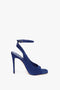 The versatile Victoria Beckham Dawn Sandal in Night Blue Suede is a sophisticated blue high-heeled shoe with an ankle strap and peep-toe design.